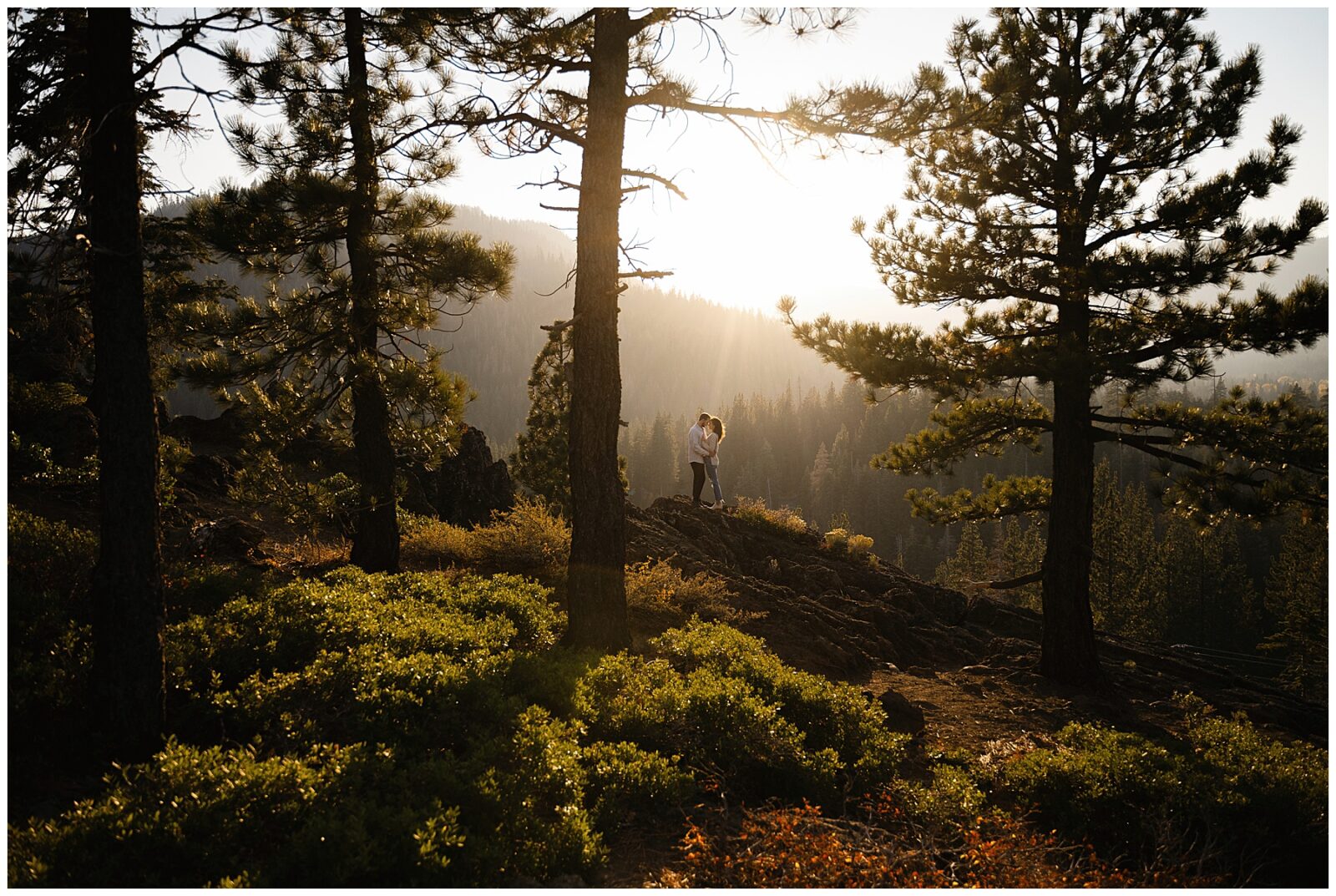 couple standing on a boulder during sunset during their lake tahoe engagement session