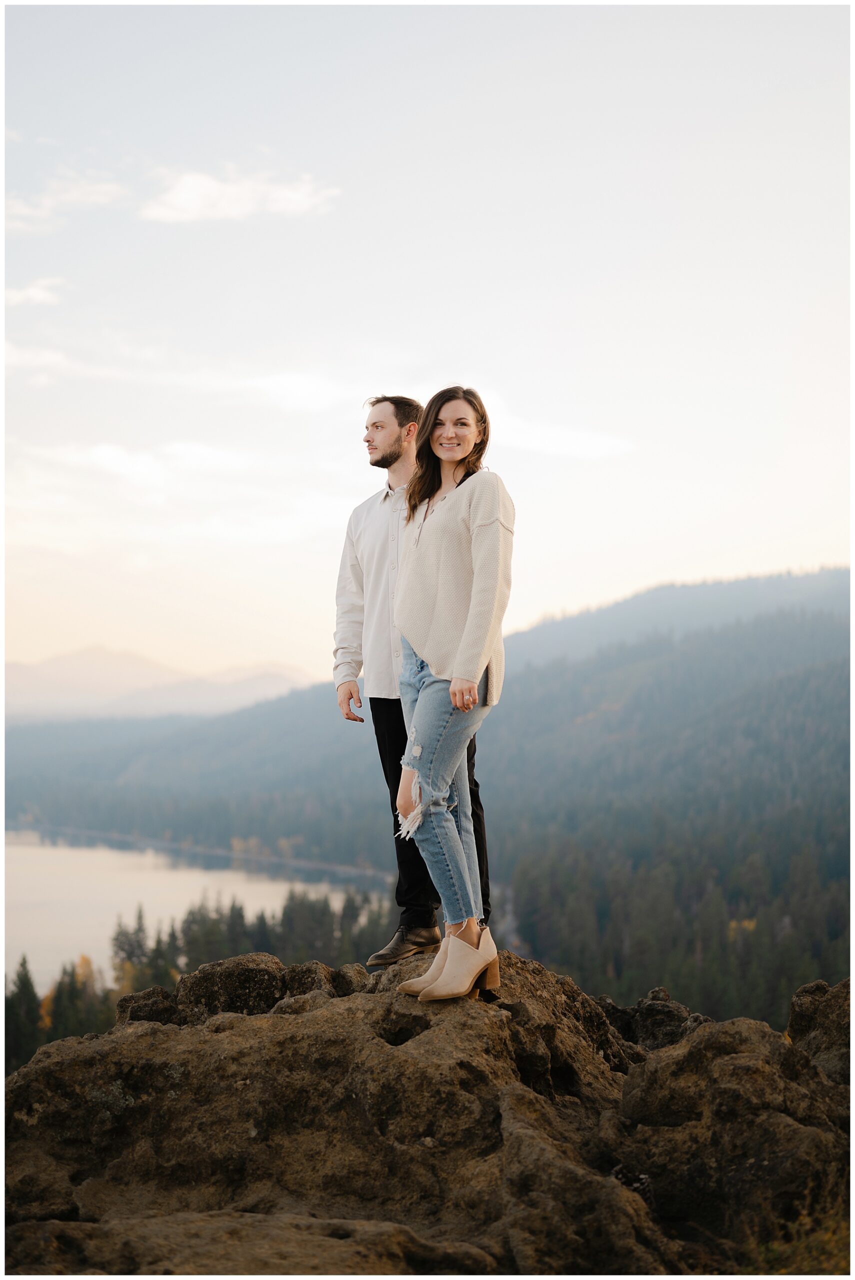 Couple standing on boulder overlooking lake tahoe